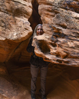Portrait of smiling female hiker in sandstone crevice on Angels Landing Trail. , Utah, USA.