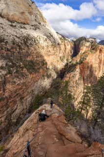 Hikers descending Angels Landing Trail holding chains. , Utah, USA.