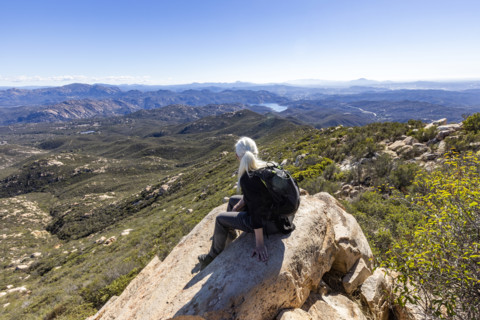 Senior blond hiker looking at view from top of Iron Mountain. Temecula, California, USA.