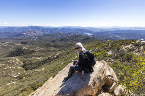 Senior blond hiker looking at view from top of Iron Mountain. Temecula, California, USA.