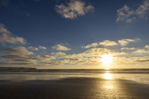Sun setting over beach and calm ocean. Oceanside, California, USA.