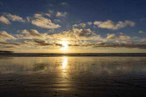Sun setting over beach and calm ocean. Oceanside, California, USA.