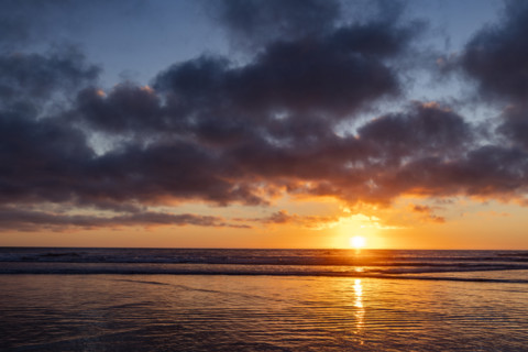 Sun setting over calm ocean. Oceanside, California, USA.