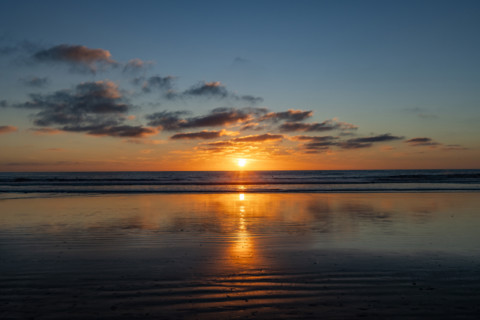 Sun setting over calm ocean. Oceanside, California, USA.