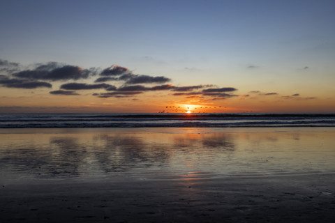 Sun setting over calm ocean. Oceanside, California, USA.