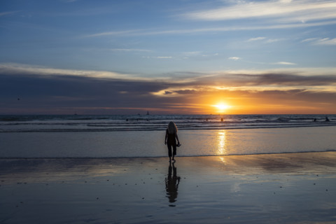 Rear view of woman walking on beach at sunset. , Guanacaste, Costa Rica.