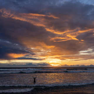 Silhouette of person with arms raise in sea at sunset. , Guanacaste, Costa Rica.