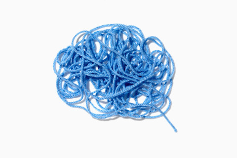 Tangled blue yarn on white background. New York City, New York State, USA.