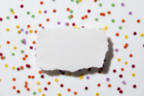 Torn white paper on confetti background. New York City, New York State, USA.