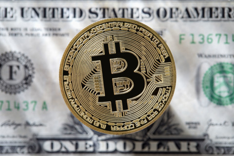 Bitcoin against one US Dollar bill. New York City, New York State, USA.