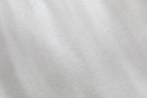 Dappled light on textured white paper. New York City, New York State, USA.