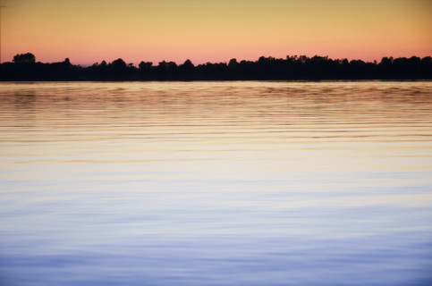 Calm Black Lake reflecting sky at sunset. Hammond, New York State, USA.