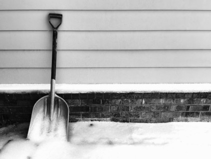 Snow shovel leaning on garage wall, black and white. Nashville, Tennessee, USA.