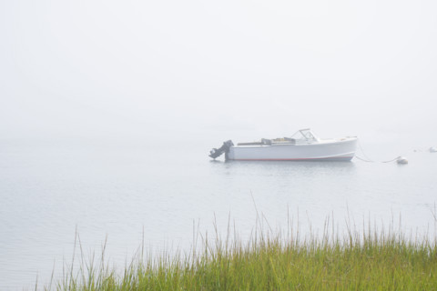 Motorboat anchored on Madaket Harbor on misty morning. Nantucket, Massachusetts, USA.