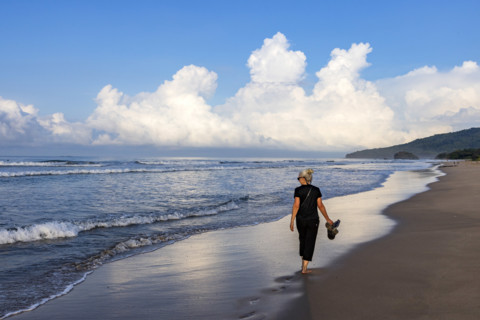 Rear view of woman walking on beach at dawn, Playa Grande, Guanacaste, Costa Rica.
