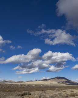 White puffy clouds above Interstate 80 crossing barren landscape, Winnemucca, Nevada, USA.