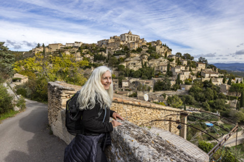 Smiling senior woman looking at old town, Gordes, Vaucluse, France.