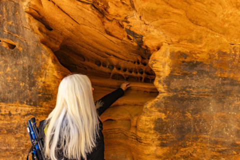 Senior blonde woman touching sandstone formations, Zion National Park, Utah, USA.
