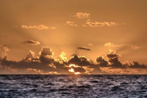Sun rising through clouds over Atlantic Ocean, Boca Raton, Florida, USA.
