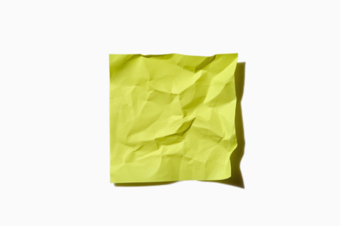 Crumpled yellow post it note on white background, New York City, New York, USA.