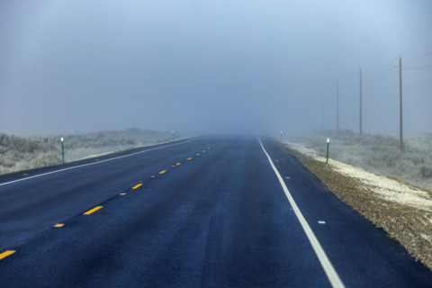 Two lane highway leading into fog bank