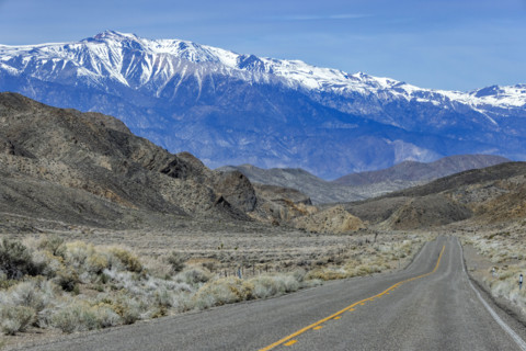 Empty two-lane highway through desert to mountains
