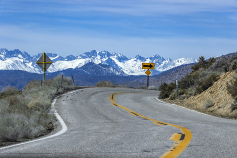 Empty two-lane highway through desert to mountains