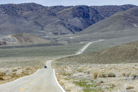 Two-lane highway through desert to mountains