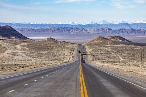 Traffic on desert highway with snowcapped mountains in distance