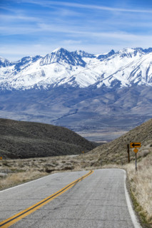 Empty two-lane highway through desert to mountains