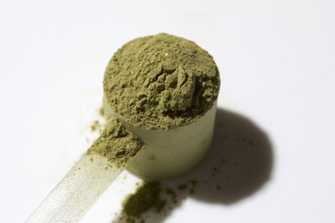 Scoop of green powder on white background