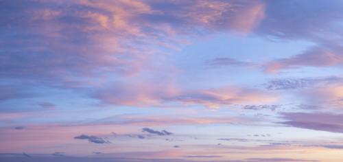 Pale pink clouds against blue sky