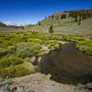 Creek flowing through valley with mountains in distance