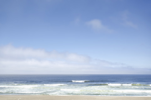 White clouds and blue sky above beach and calm ocean