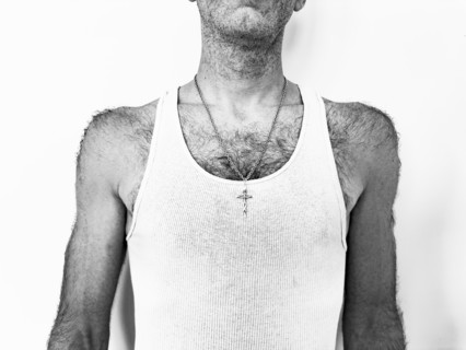 Studio shot of man in tank top with crucifix on chain, black and white