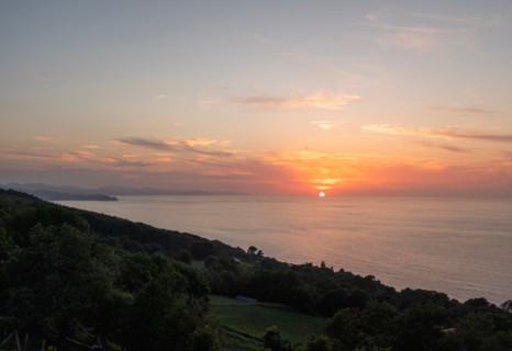 Sunset over calm sea and green hill. San Sebastian, Gipuzkoa, Spain