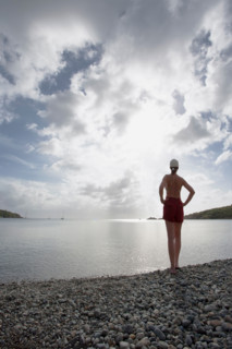 Rear view of woman on pebble beach facing calm sea. St. John, United States Virgin Islands, United