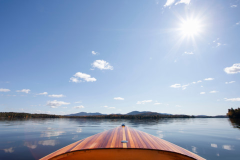 Wooden boat on calm Upper Saranac Lake on sunny day. Santa Clara, New York, United States