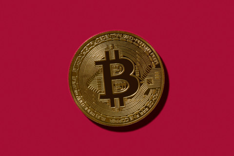 Golden Bitcoin on red background. New york City, New York State, United States