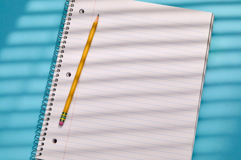 Spiral notebook and pencil on blue background. New York City, New York State, United States