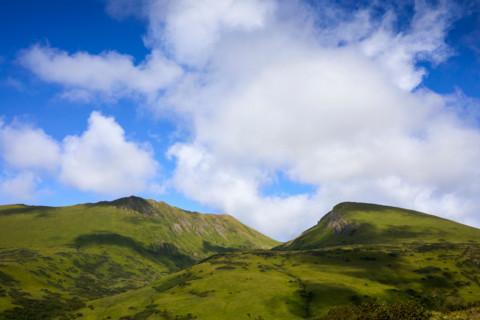 White puffy clouds above green mountains. Kodiak, Alaska, United States