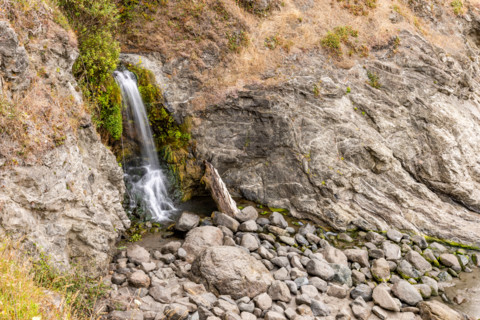 Waterfall running onto beach on Oregon Coast. Gold Beach, Oregon, United States