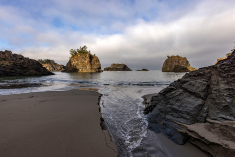 Tide running up creek channel on beach along Oregon Coast. Gold Beach, Oregon, United States