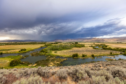Storm clouds over fields and winding river. Bellevue, Idaho, United States