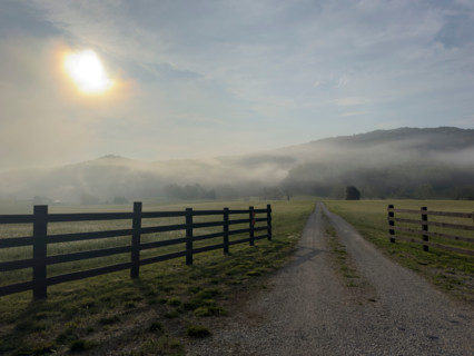 Dirt road and fields in mist at sunrise. Blacksburg, Virginia, United States