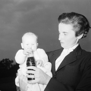 Coca Cola baby. Wendy Winter holds a bottle of Coca Cola up in front of her baby. Kenya, 22 August