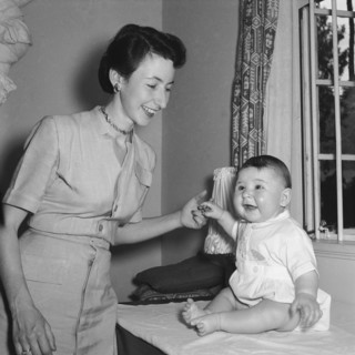 Playing with Tubby Block's baby. Interior shot of a smiling woman holding hands with Tubby Block's