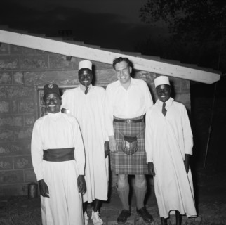 Christening cheer. Exterior night shot of Peter Buchanan and three African servants, all smiling