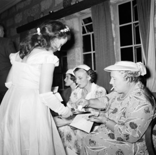 Anyone for cake?. A bridesmaid offers cake to a group of smoking female guests at the