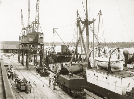 Unloading a train from SS Harmonides. Cranes onboard SS Harmonides hoist a locomotive boiler onto